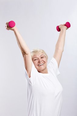 Mature woman lifts weights on a white background clipart