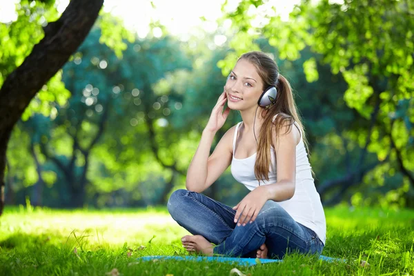 有吸引力的年轻女孩 用耳机在公园 — Φωτογραφία Αρχείου