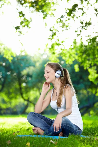 公園で音楽を聴く若い魅力的な女の子 — ストック写真