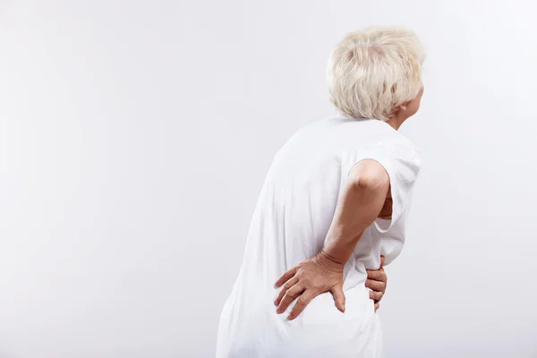 Uma mulher idosa com dor nas costas Fotos De Bancos De Imagens