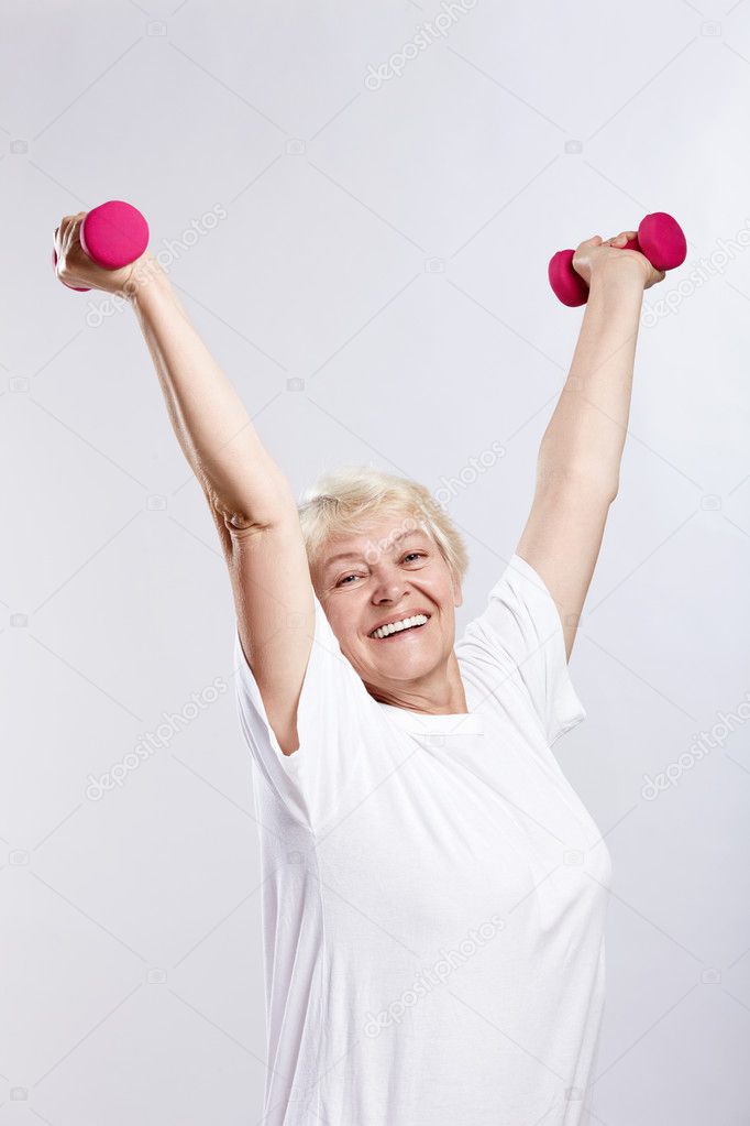 Mature woman lifts weights on a white background