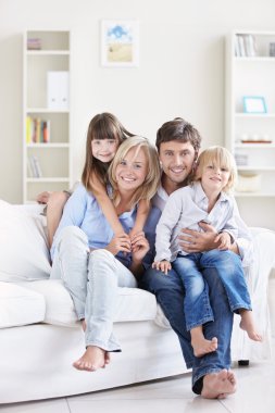 A happy family with children on a white sofa at home clipart