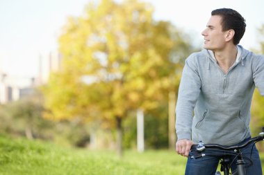 A young man on a bicycle looks into the distance clipart