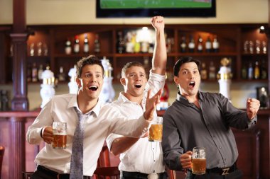 Young with beer watching football in a bar clipart