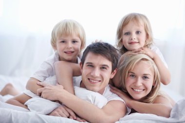 A family with two children on a bed in the bedroom clipart