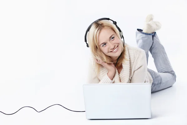 Chica joven en auriculares con un ordenador portátil —  Fotos de Stock