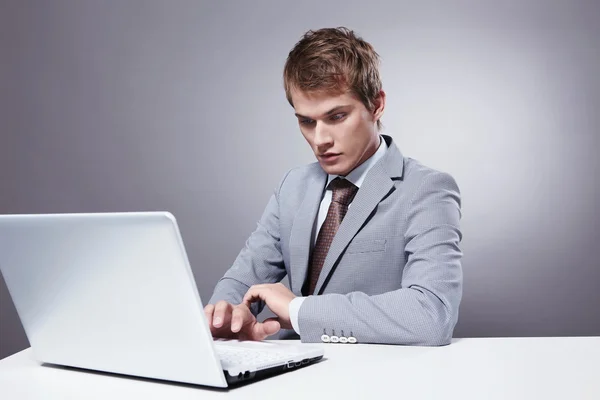 Fiatal Üzletember Dolgozik Laptop Egy Szürke Háttér — Stock Fotó