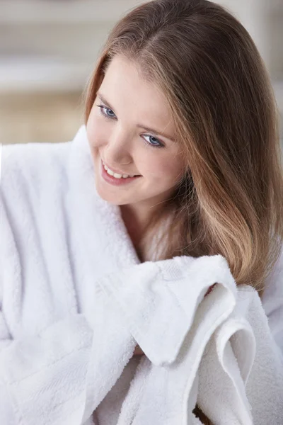 Μια νεαρή κοπέλα σε ένα άσπρο παλτό στεγνώνει τα μαλλιά με μια πετσέτα — Φωτογραφία Αρχείου