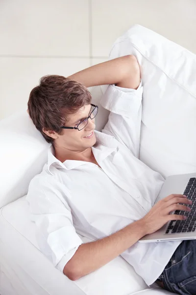 Ein Junger Mann Auf Der Couch Mit Einem Laptop Arbeitet — Stockfoto