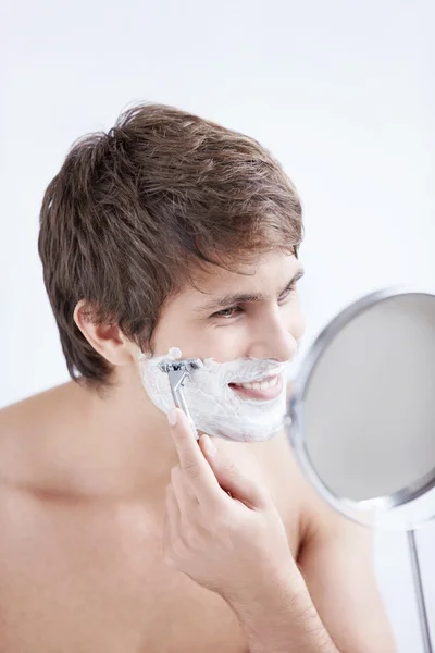 Νεαρός Άνδρας Ξύρισμα Στον Καθρέφτη Λευκό Φόντο — Φωτογραφία Αρχείου