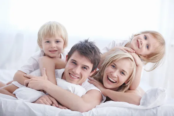 Μια Ευτυχισμένη Οικογένεια Στο Λευκό Κρεβάτι Στην Κρεβατοκάμαρα Royalty Free Εικόνες Αρχείου