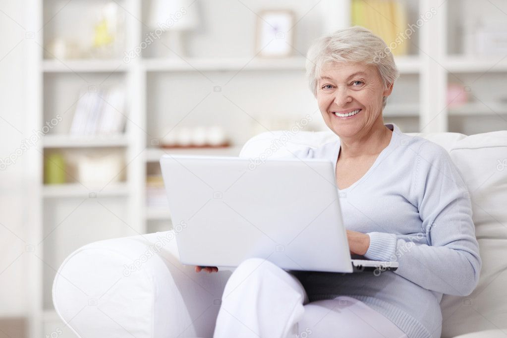 A smiling middle-aged woman with a laptop at home