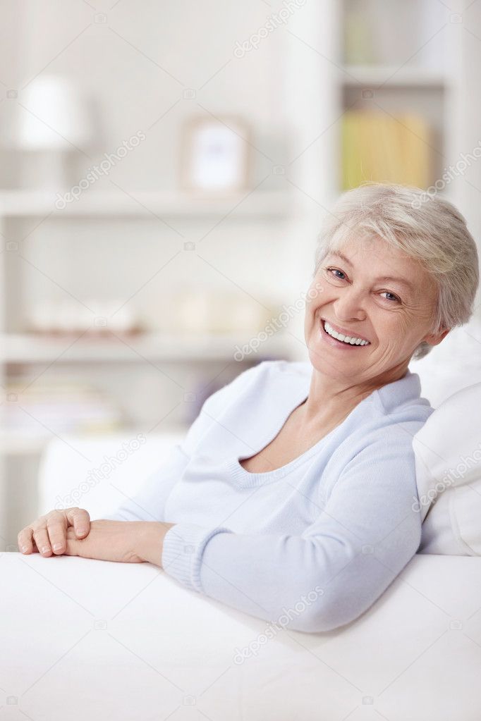 Smiling elderly woman at home on the couch
