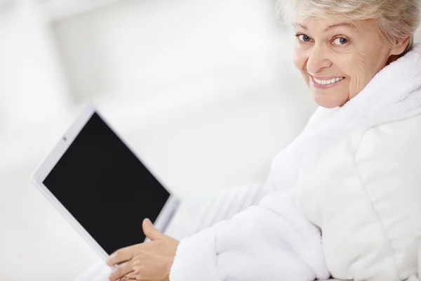 Зрелая женщина улыбается с ноутбуком — стоковое фото