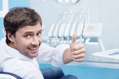 Attractive man in a the dental chair clipart