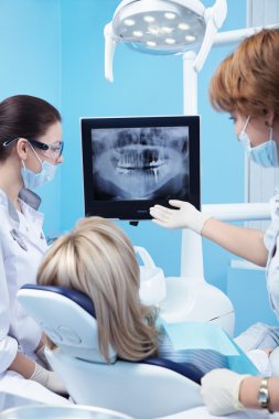 Dentist shows a patient x-ray of teeth clipart