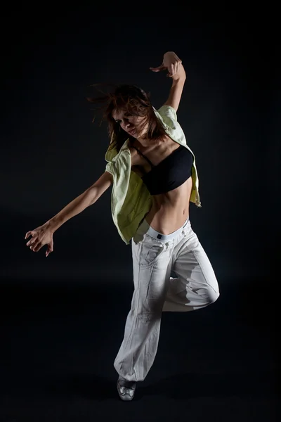 stock image Young woman dancing on black background