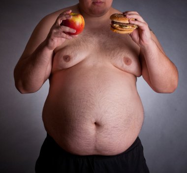 Fat man with burger and apple, studio shot clipart