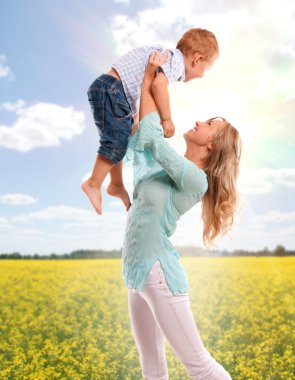 Portrait of happy mother with joyful son over spring flower field