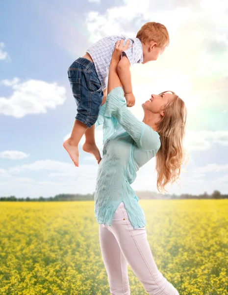 Retrato de mãe feliz com filho alegre sobre o campo de flores da primavera — Fotografia de Stock
