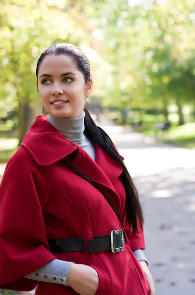 Young pretty woman in red coat at the autumn park. — Stock Photo, Image