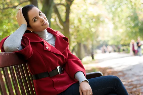 Fiatal kaukázusi nő ül egy fa pad a parkban, — Stock Fotó