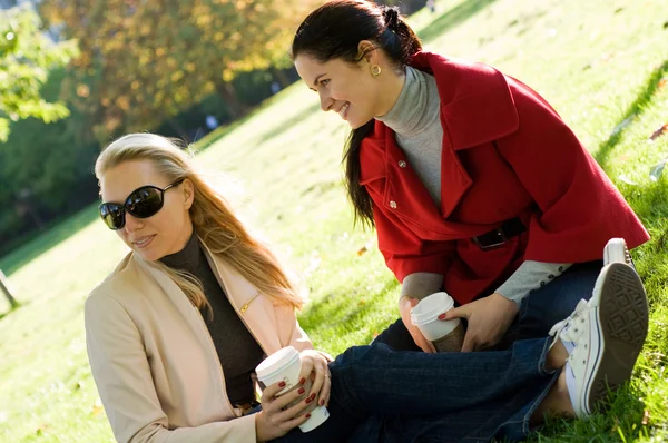 在喝咖啡的两名年轻妇女在一起闯进公园 — 图库照片