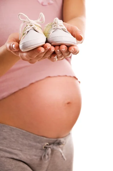 Mujer embarazada sosteniendo un par de zapatos blancos para bebé — Foto de Stock