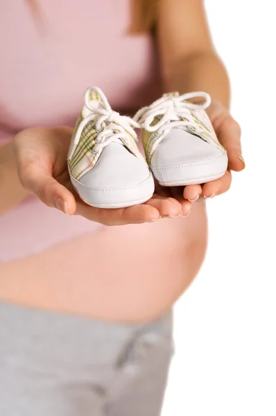 Mulher grávida segurando par de sapatos brancos para bebê — Fotografia de Stock
