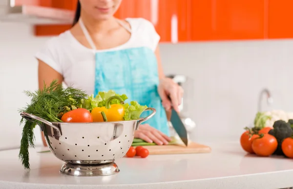 Mladá žena v její kuchyni řezání přísady — Stock fotografie