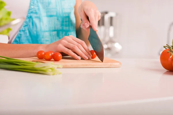 Ung kvinne som skjærer grønnsaker på et kjøkken – stockfoto