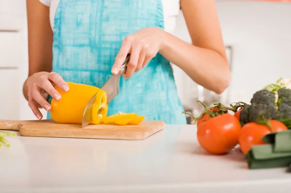 Mujer joven cortando verduras en una cocina — Foto de Stock