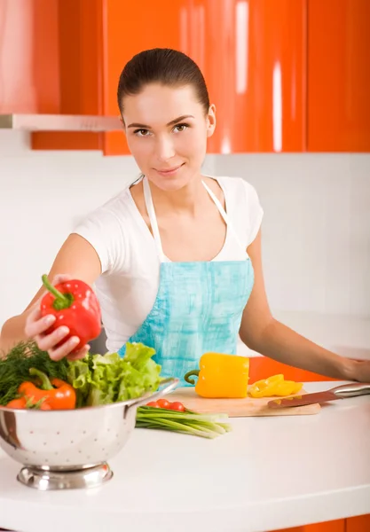 Jovem mulher em sua cozinha cortando legumes — Fotografia de Stock