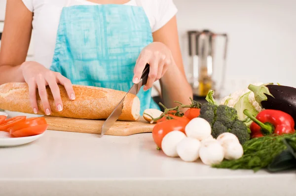 Mujer cortando pan en la cocina — Foto de Stock