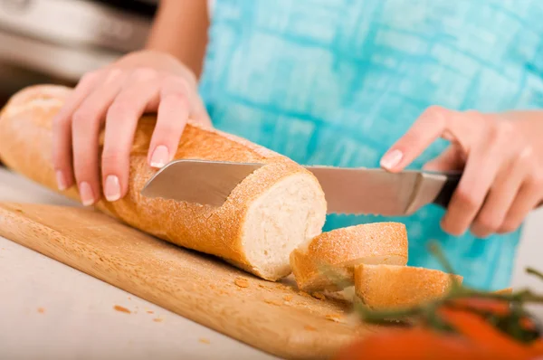 Kobieta cięcia chleba w kuchni — Zdjęcie stockowe