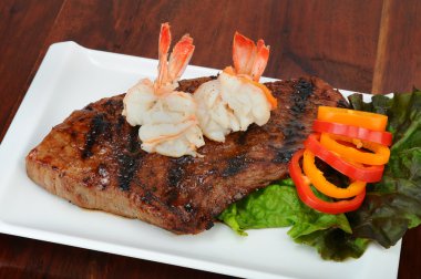 Rib-eye steak with boiled shrimp on top. clipart