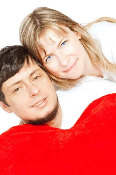 Pareja feliz sosteniendo almohada roja sobre blanco — Foto de Stock