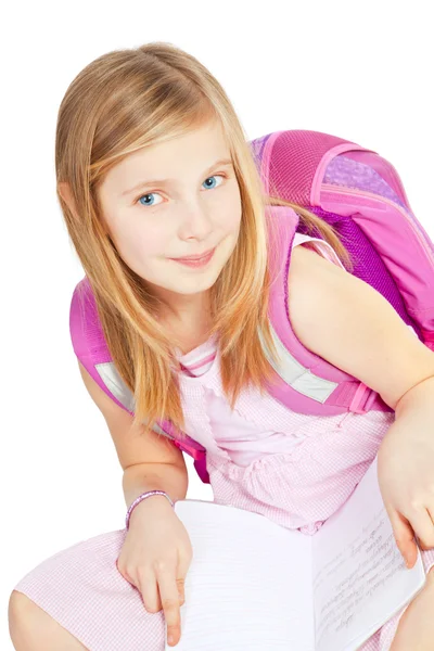 Schoolgirl sitting with backpack and doing homework over white — Stock Photo, Image