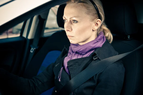 Mujer sentada en coche con los ojos enfocados en la carretera — Foto de Stock
