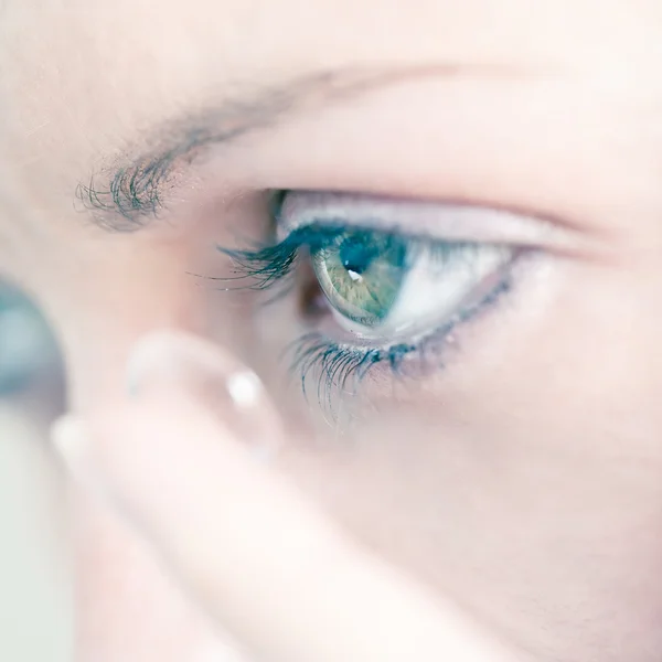 Молодая женщина вставляет контактную линзу в глаз крупным планом Стоковая Картинка