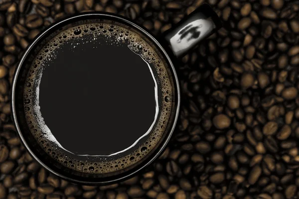 Caneca preta de café e grãos espalhados — Fotografia de Stock
