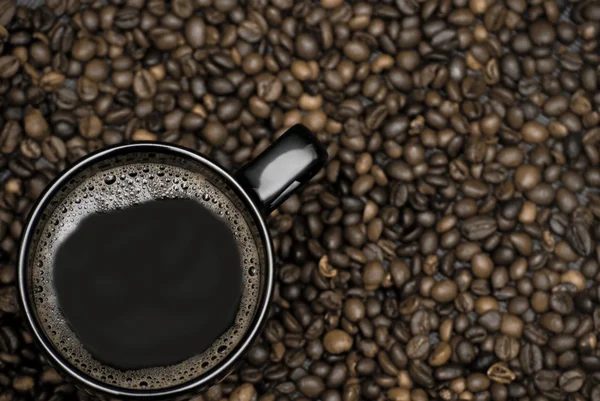 Cană neagră de cafea și fasole împrăștiată — Fotografie, imagine de stoc