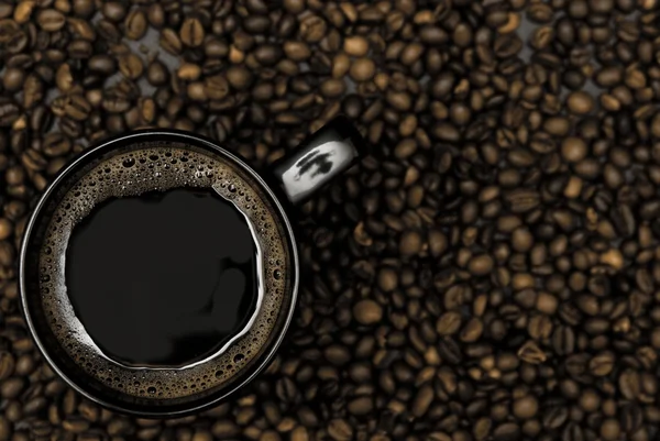 Taza negra de café y granos dispersos —  Fotos de Stock
