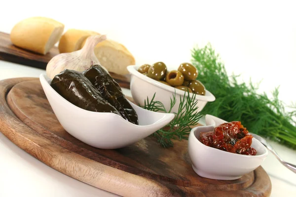 Olives, stuffed vine leaves and dried tomatoes — Stock Photo, Image