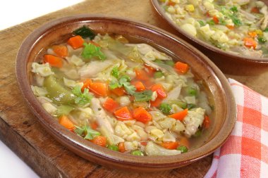 A chicken soup with shell pasta and vegetables clipart