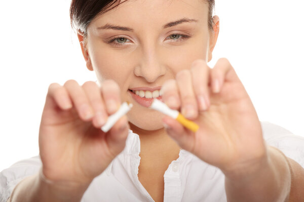 Молодая женщина разбивает сигарету на белом фоне
