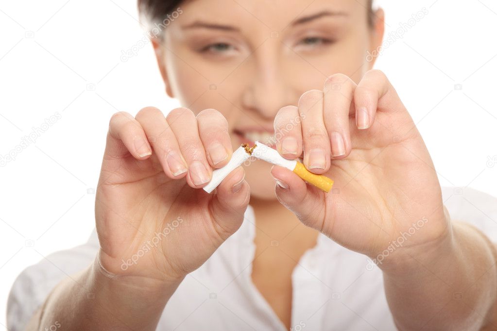 Young woman breaking cigarette over white background