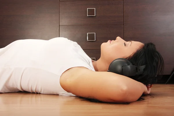 Happy woman with headphones lying down on flore — Stock Photo, Image
