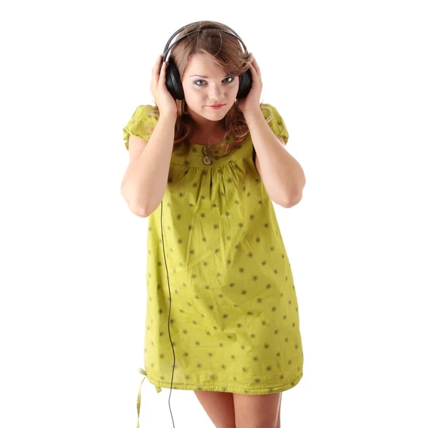 白で隔離され 大きなヘッドホンで音楽を聴く緑のドレスで美しい十代の少女 — ストック写真