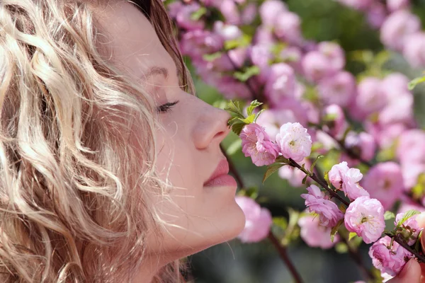 Hermosa mujer rubia entre flores rosadas —  Fotos de Stock